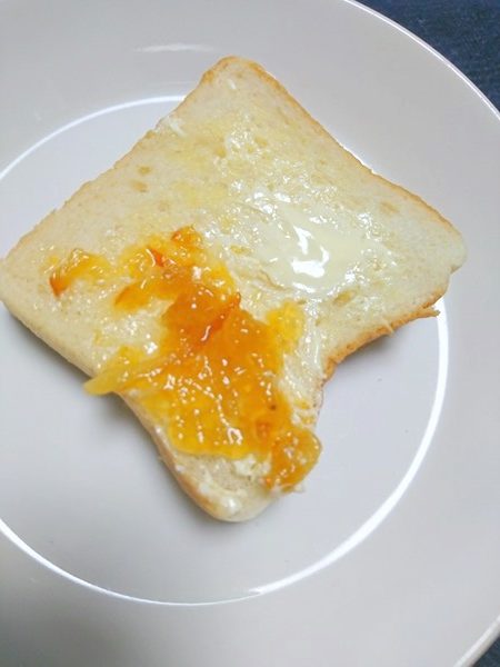 マーガリンとオーガニックオレンジマーマレードを塗った食パン