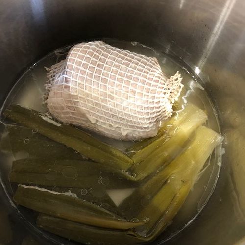 圧力鍋の中の加熱されたチャーシュー用豚肉とネギ