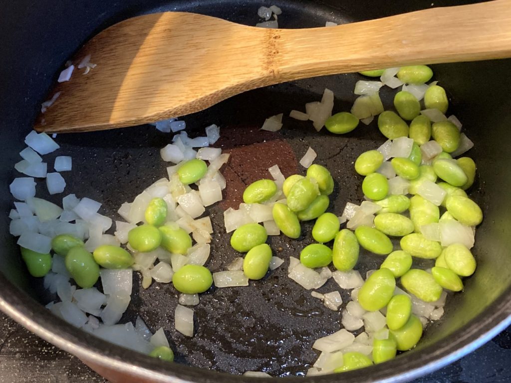 玉ねぎと枝豆をフライパンで炒める