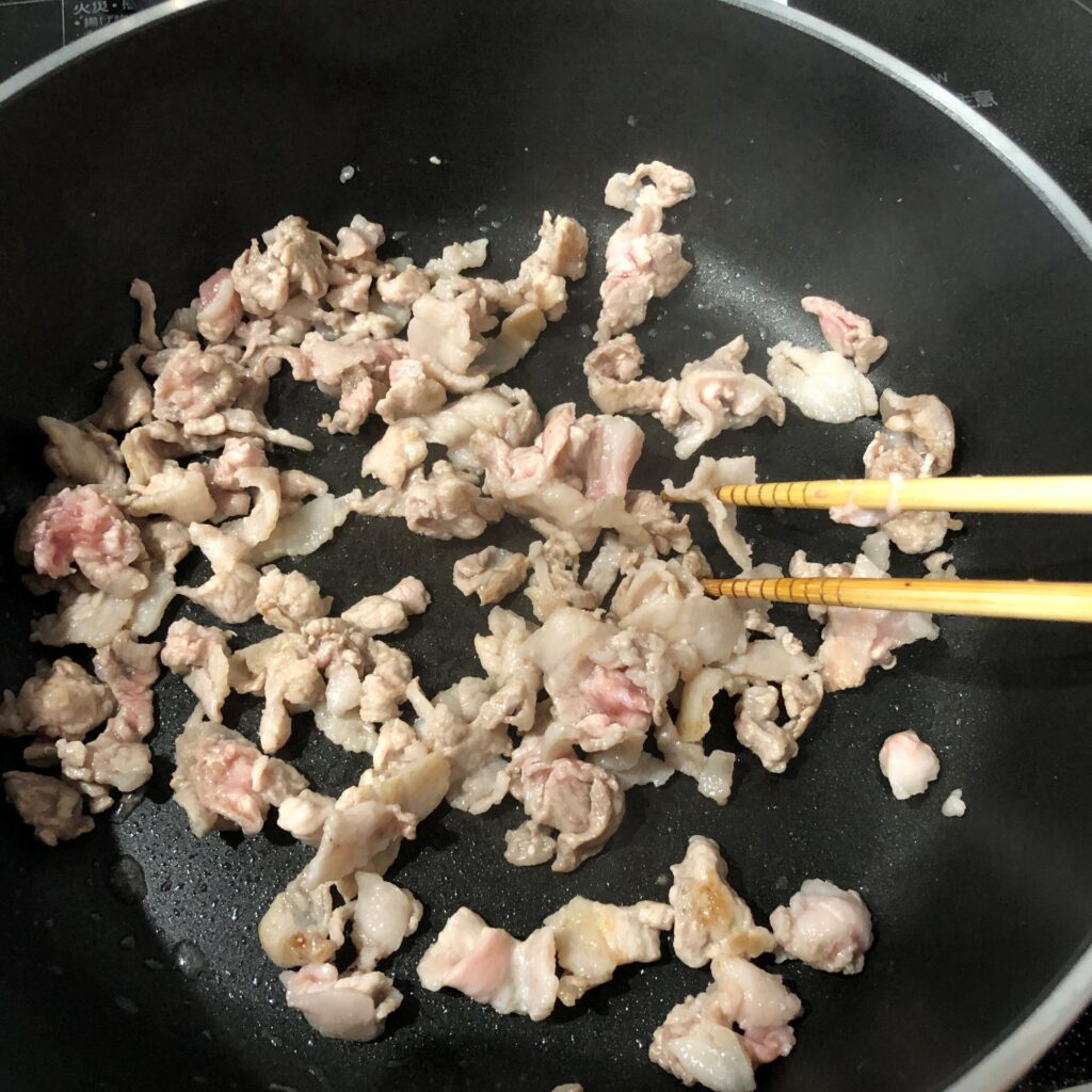 刻んだ豚肉をフライパンで炒める