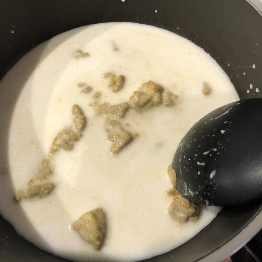 鍋でココナツミルクとグリーンカレーペーストを混ぜ煮込む