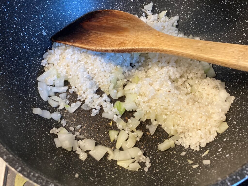 フライパンで生米と玉ねぎを炒める