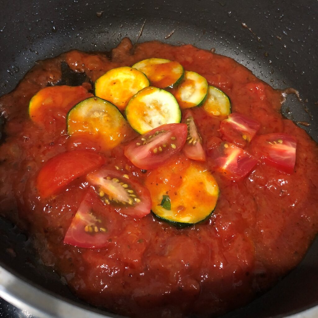 フライパンにトマトソースをカットした生トマトを入れる