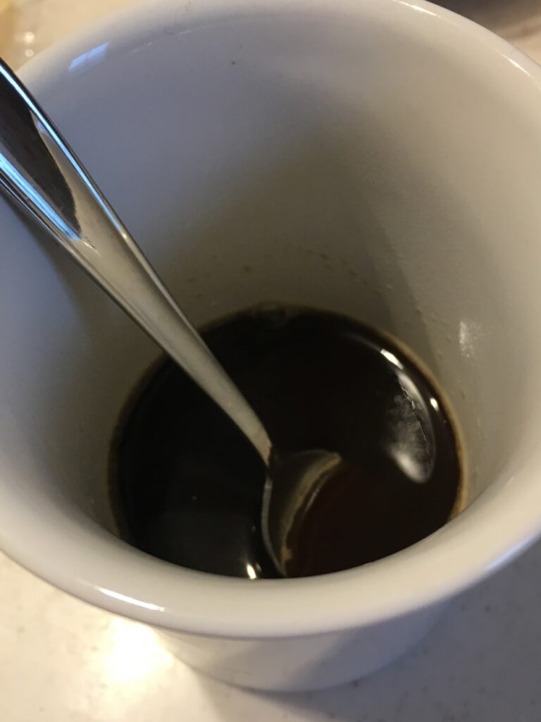 コップでインスタントコーヒーを熱湯で溶かす
