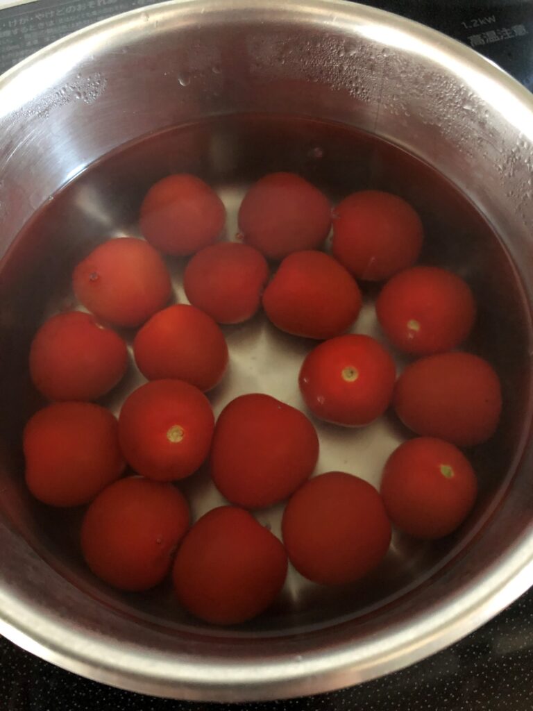 沸騰したお湯にトマトを入れる