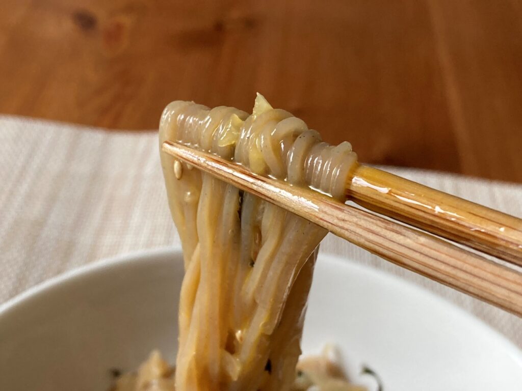 冷麺の混ぜそばを箸で持ち上げたアップ