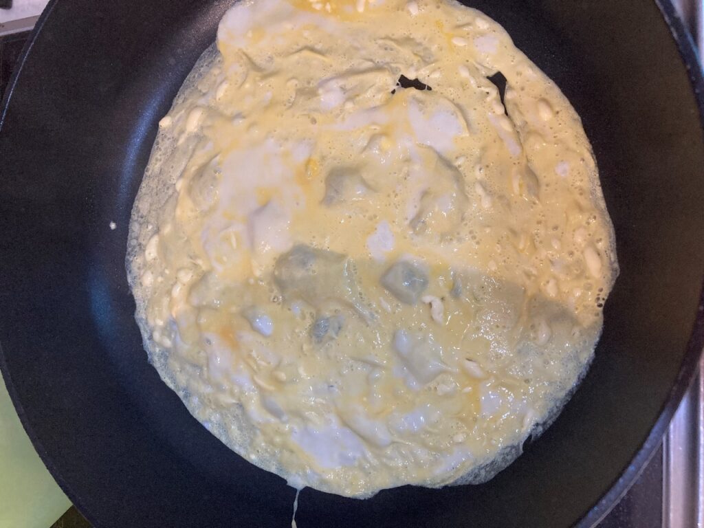 温めたフライパンに卵液を広げてオムレツの準備をする