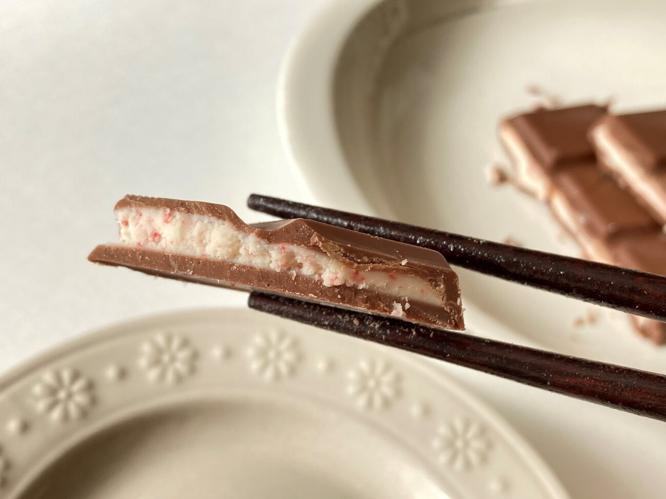 箸で持ち上げた業務スーパーのミルクチョコレートストロベリーヨーグルトフィリング断面のアップ