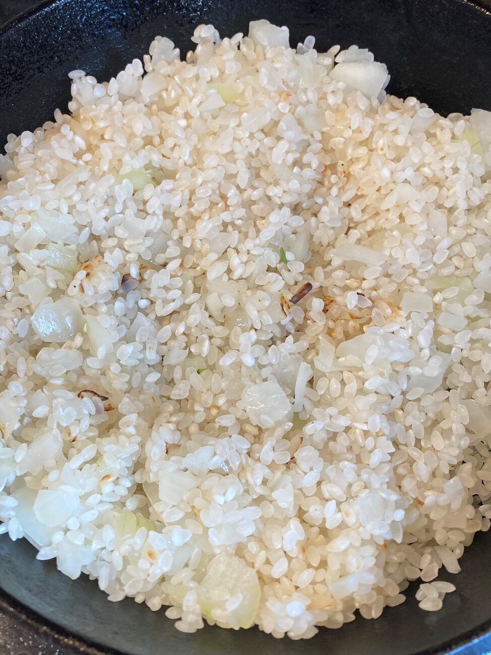 炒めた玉ねぎに生米を加えて炒める