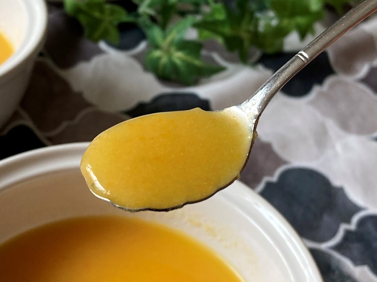 スプーンですくい上げた業務スーパーのオレンジブレンドジュースで作った人参とオレンジの冷製スープのアップ