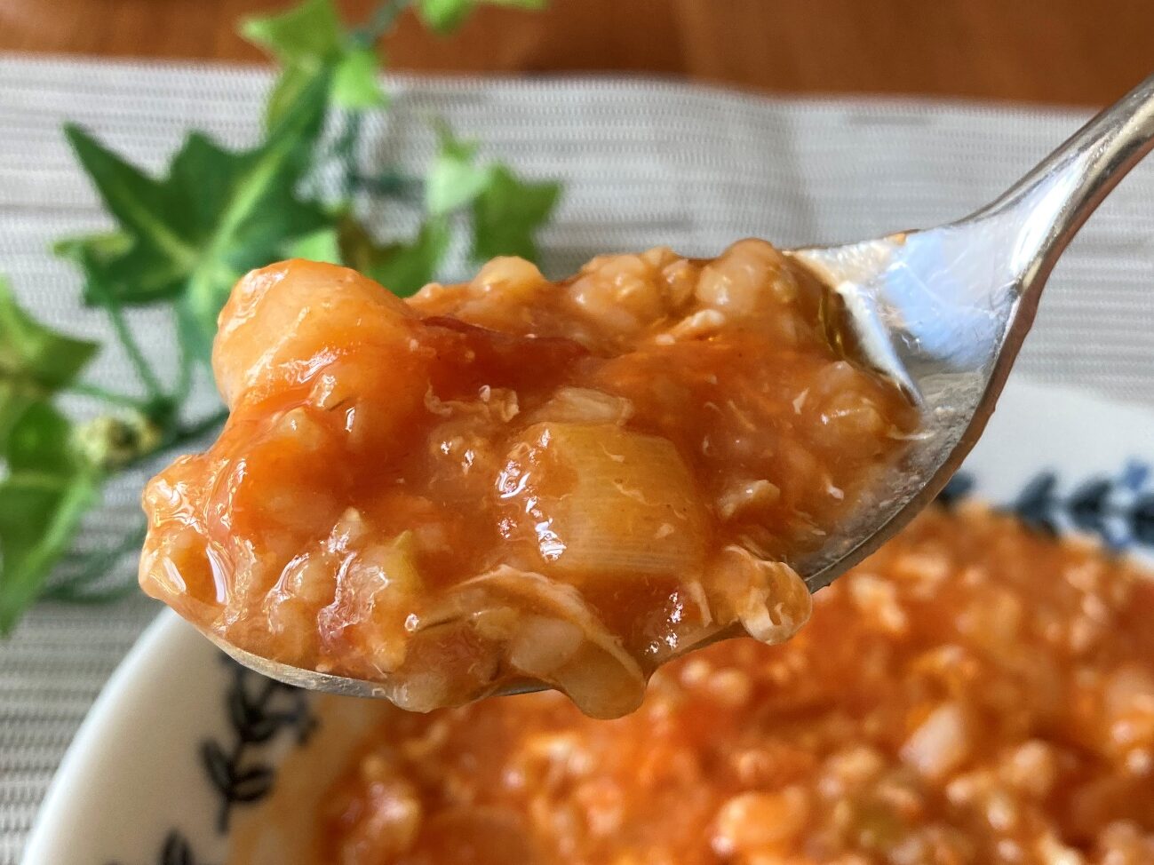 スプーンですくい上げた業務スーパーの玄米トマトリゾットで作ったトマトの中華粥のアップ