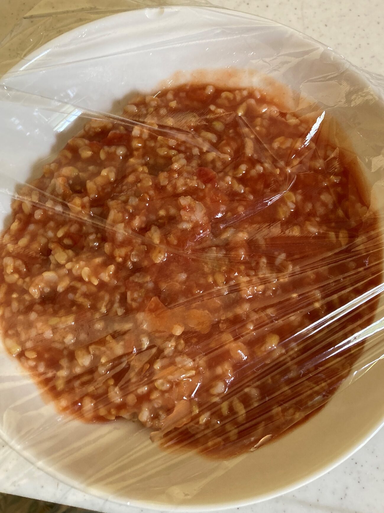 器にいれてラップをかけたレンジ加熱前の玄米トマトリゾット