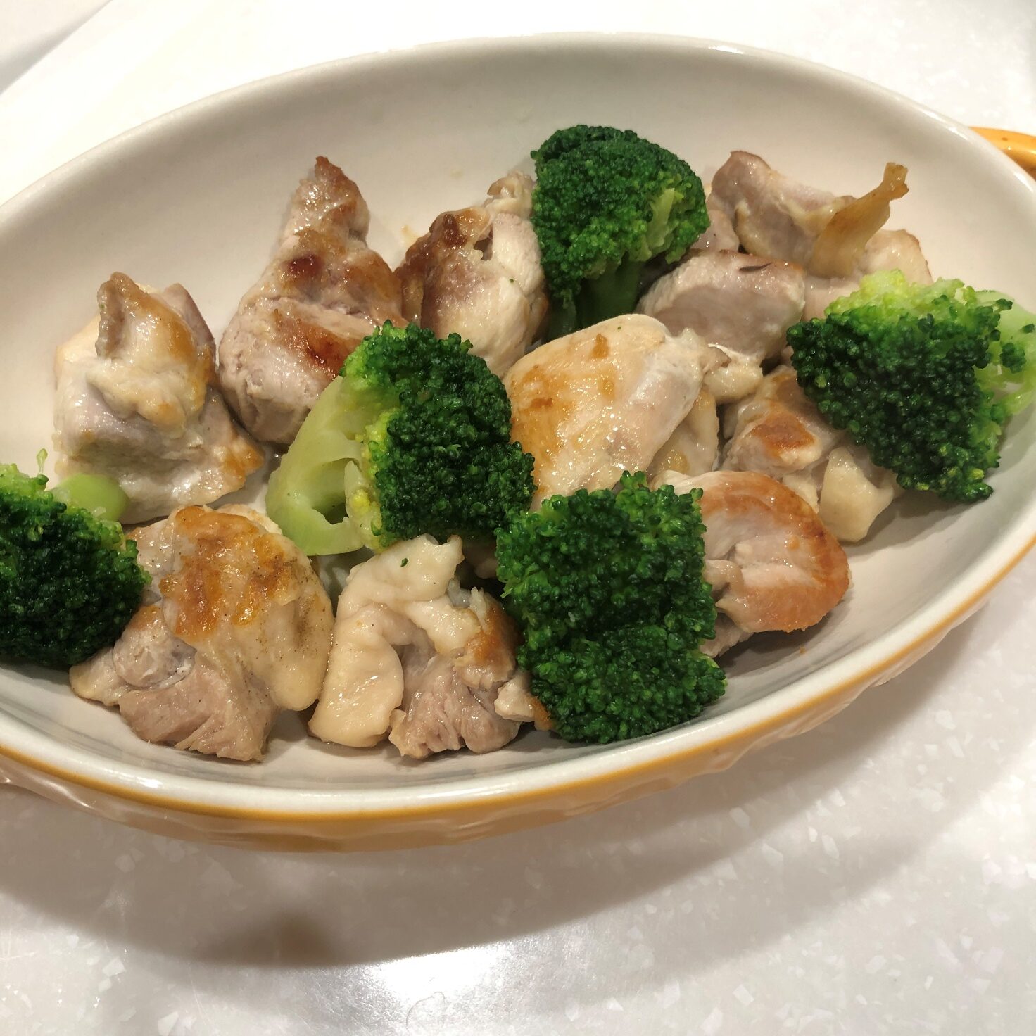 グラタン皿に焼き色がついた鶏もも肉と加熱したブロッコリーを入れる