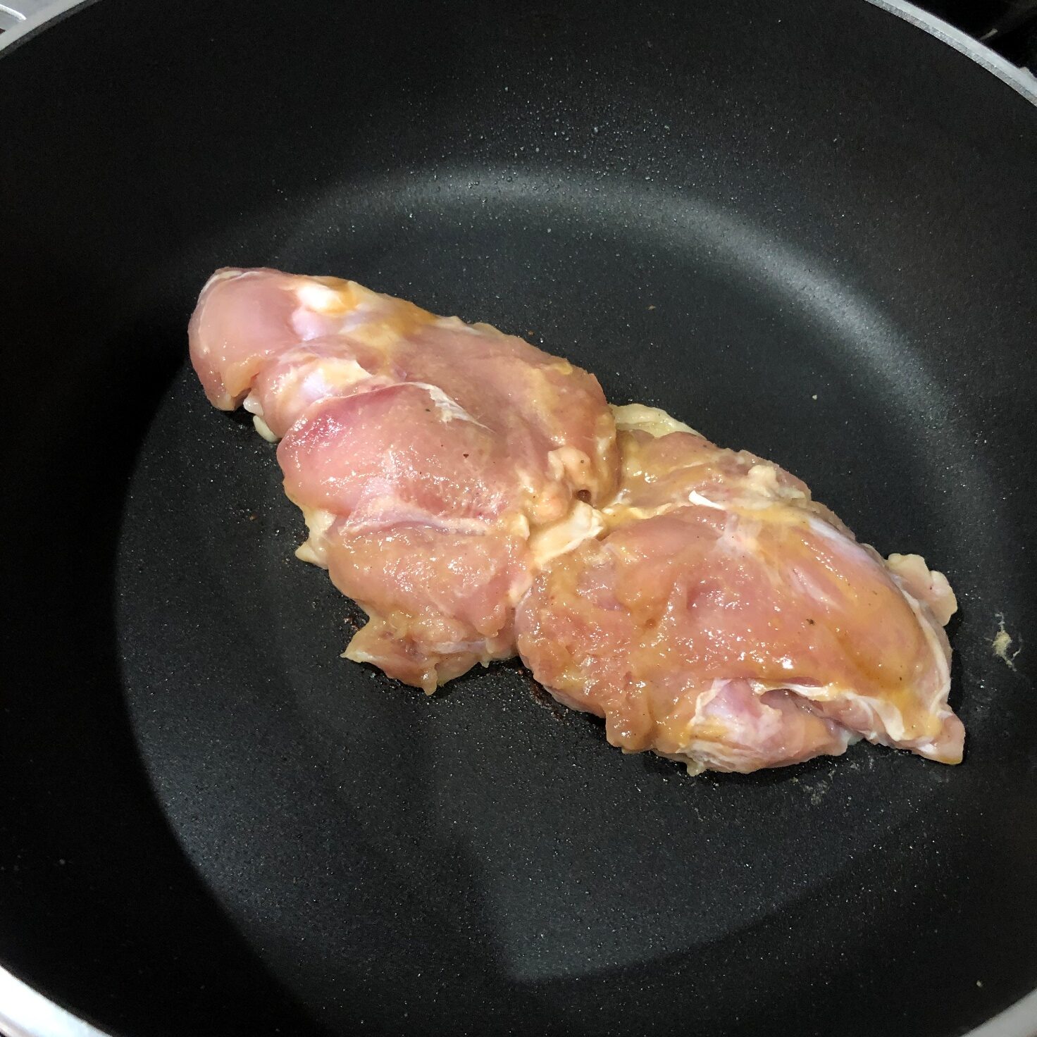 「本場タイの味 万能調味料」に漬け込んだ鶏もも肉をフライパンに入れる