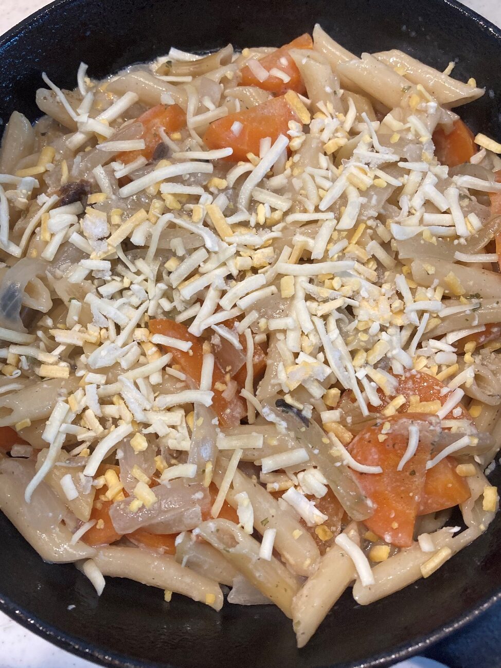 茹で上がったペンネと野菜をスキレットに移し、ピザ用チーズを散らす