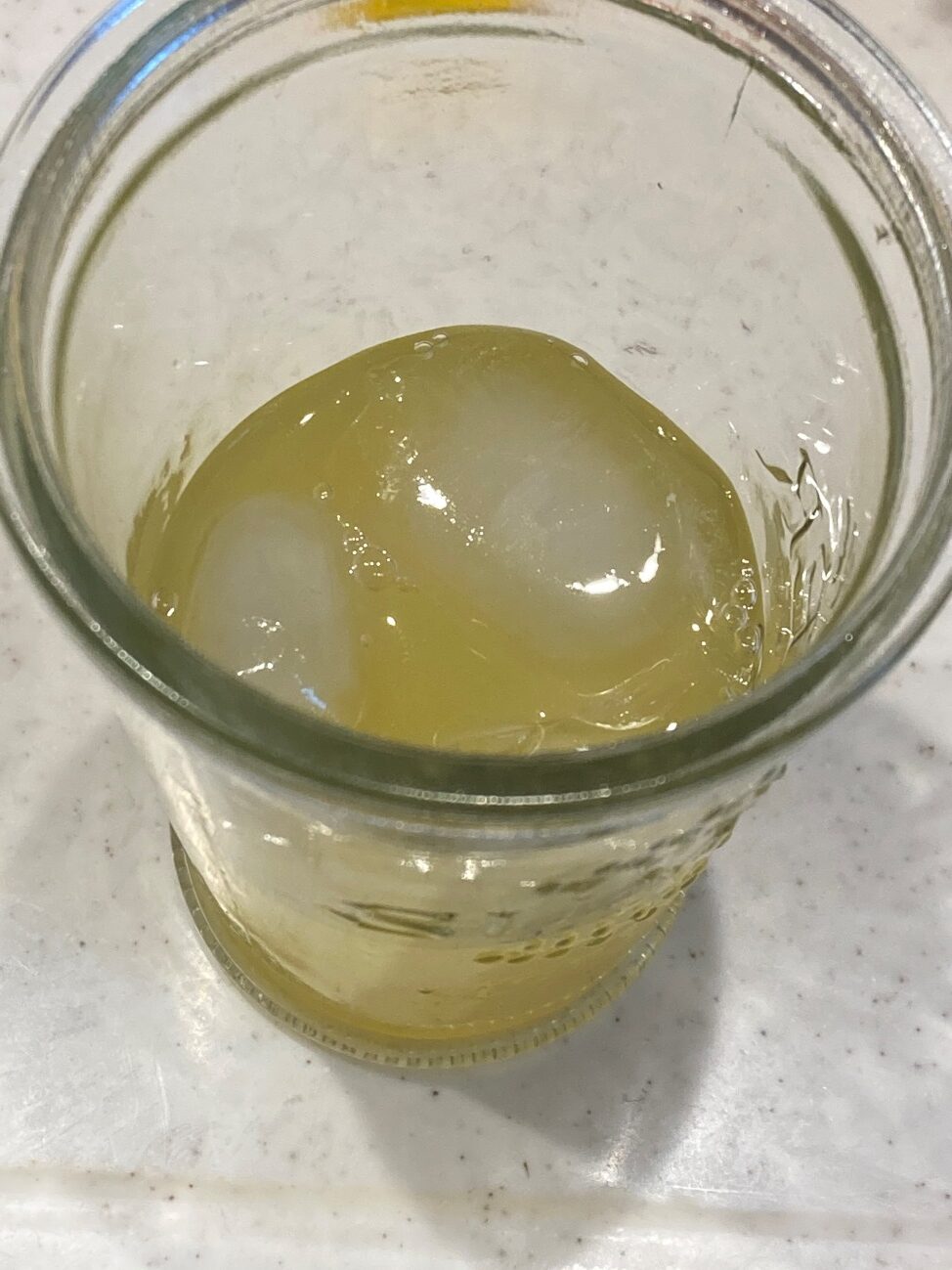 氷を入れたグラスにオレンジジュースを注ぐ