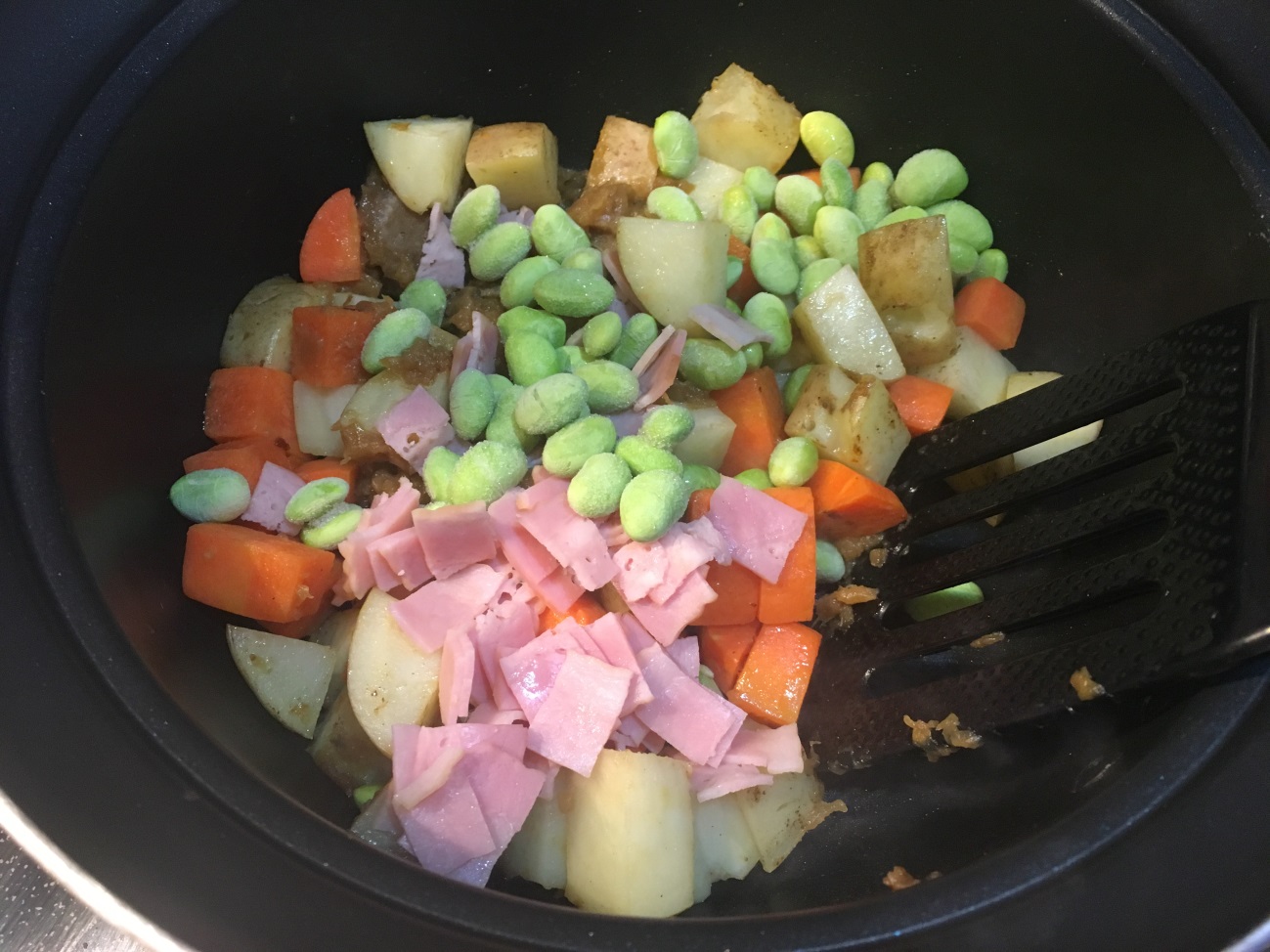 鍋で人参・じゃがいもを炒めたあと、オニオンソテー・ベーコン・冷凍枝豆を加える