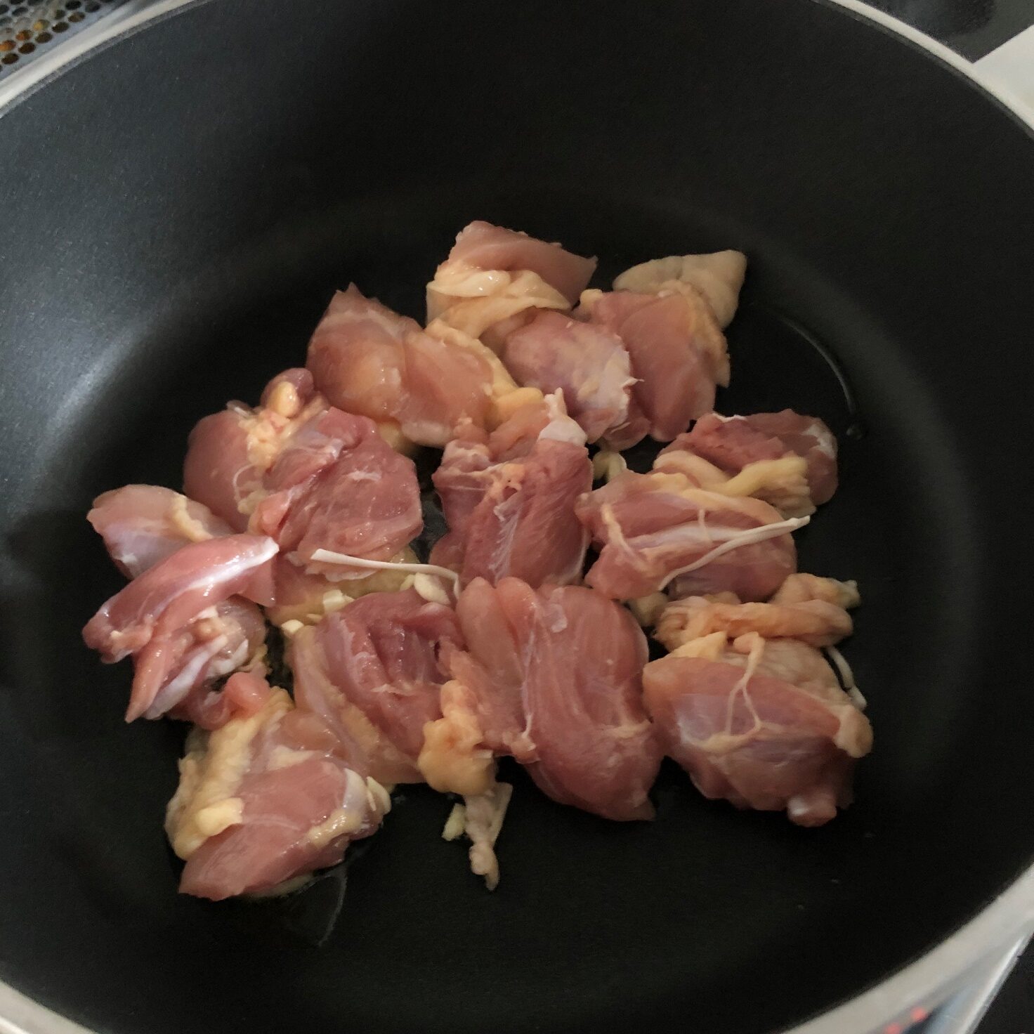 フライパンで一口大に切った鶏肉とみじん切りのにんにくを炒める