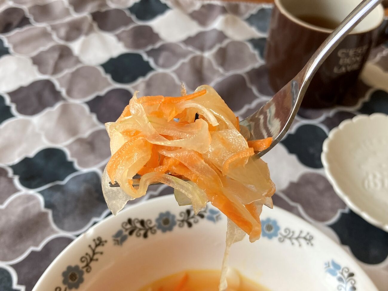 フォークで持ち上げた業務スーパーの韓国冷麵のスープで作った新玉ねぎと人参のピリ辛マリネのアップ