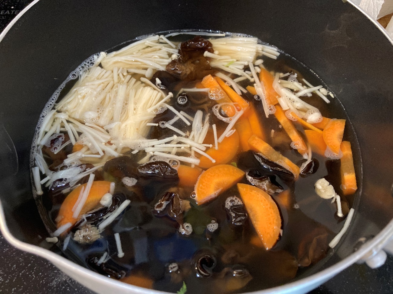 鍋に韓国冷麺のスープ・水・人参・きくらげ・えのきを入れる