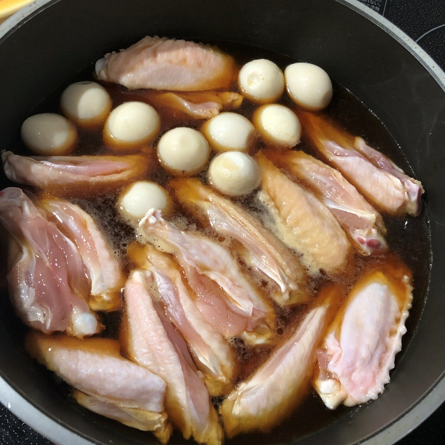 ゆずぽん酢とみりんを入れた鍋に、うずら卵と手羽中を入れる