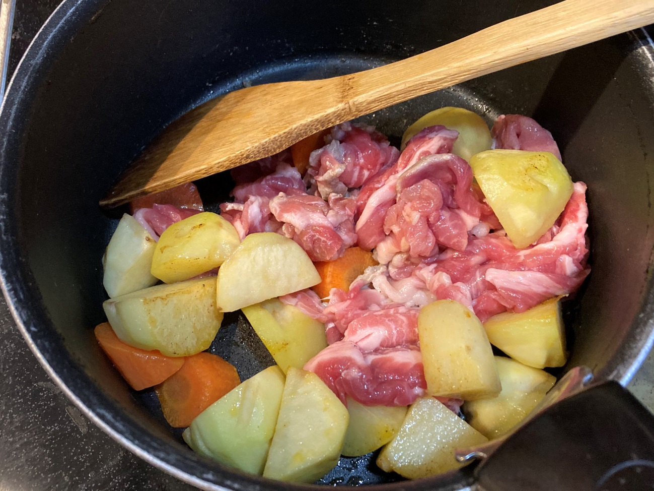 鍋でじゃがいもと人参を炒めてから、豚肉を加える