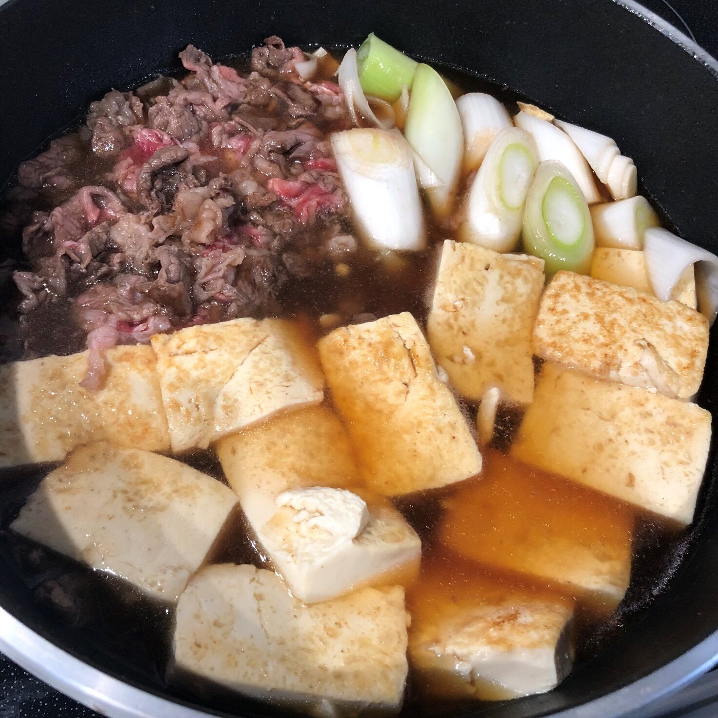 豆腐をフライパンに戻して、すき焼きのたれと水を加える