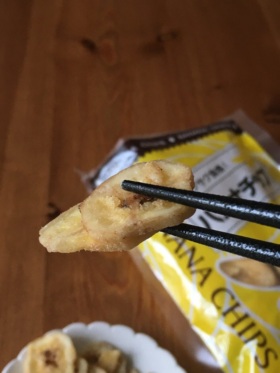 箸で持ち上げた業務スーパーのバナナチップのアップ