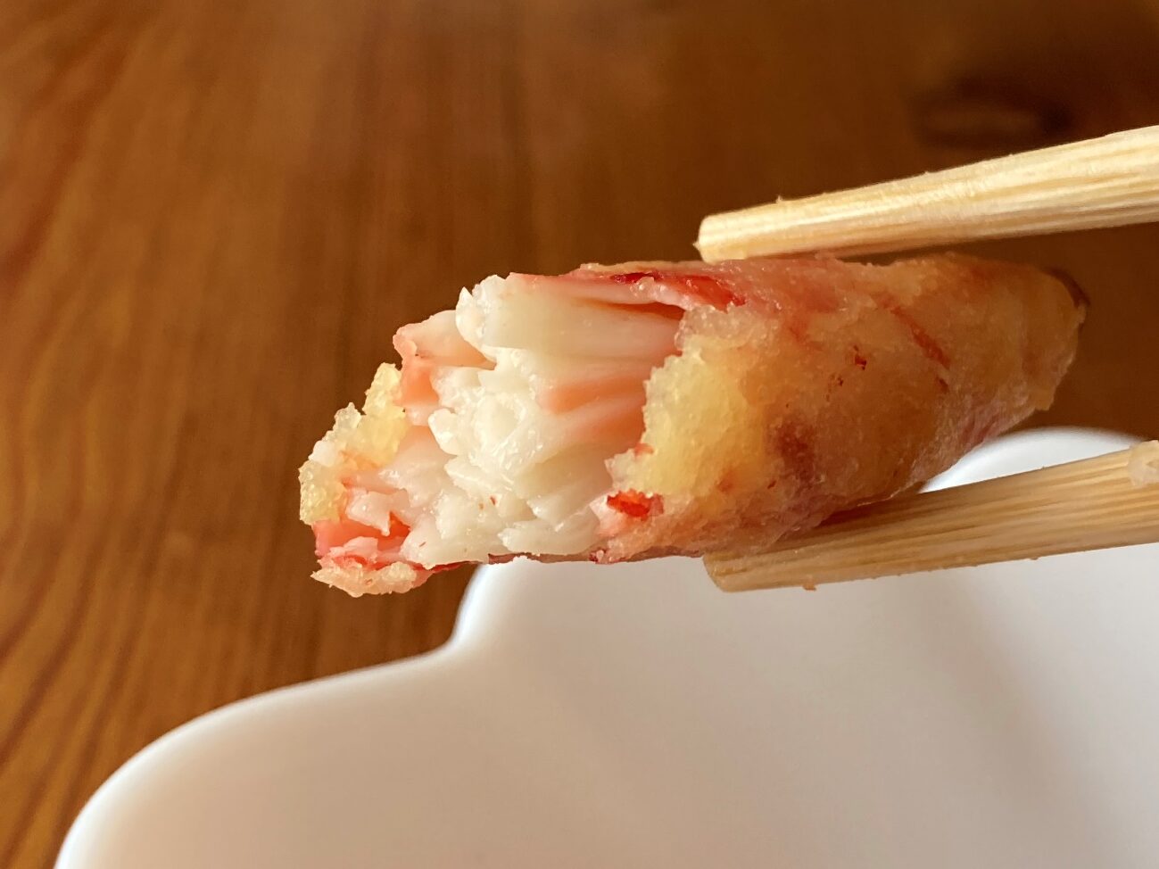 箸で持ち上げた焼いた業務スーパーのかにかま棒身天ぷらのアップ