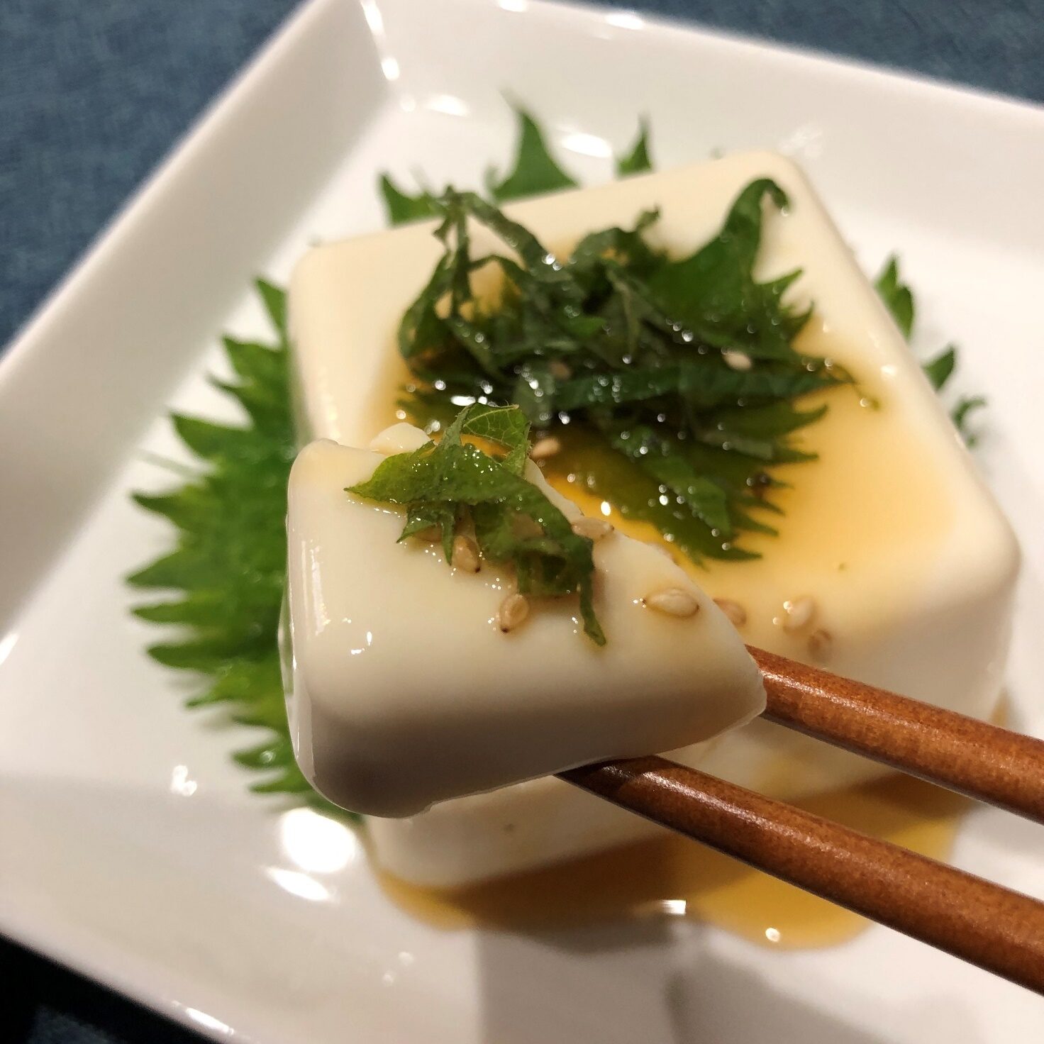 箸で持ち上げた業務スーパーのノンオイルドレッシング青じそをかけた豆腐のアップ