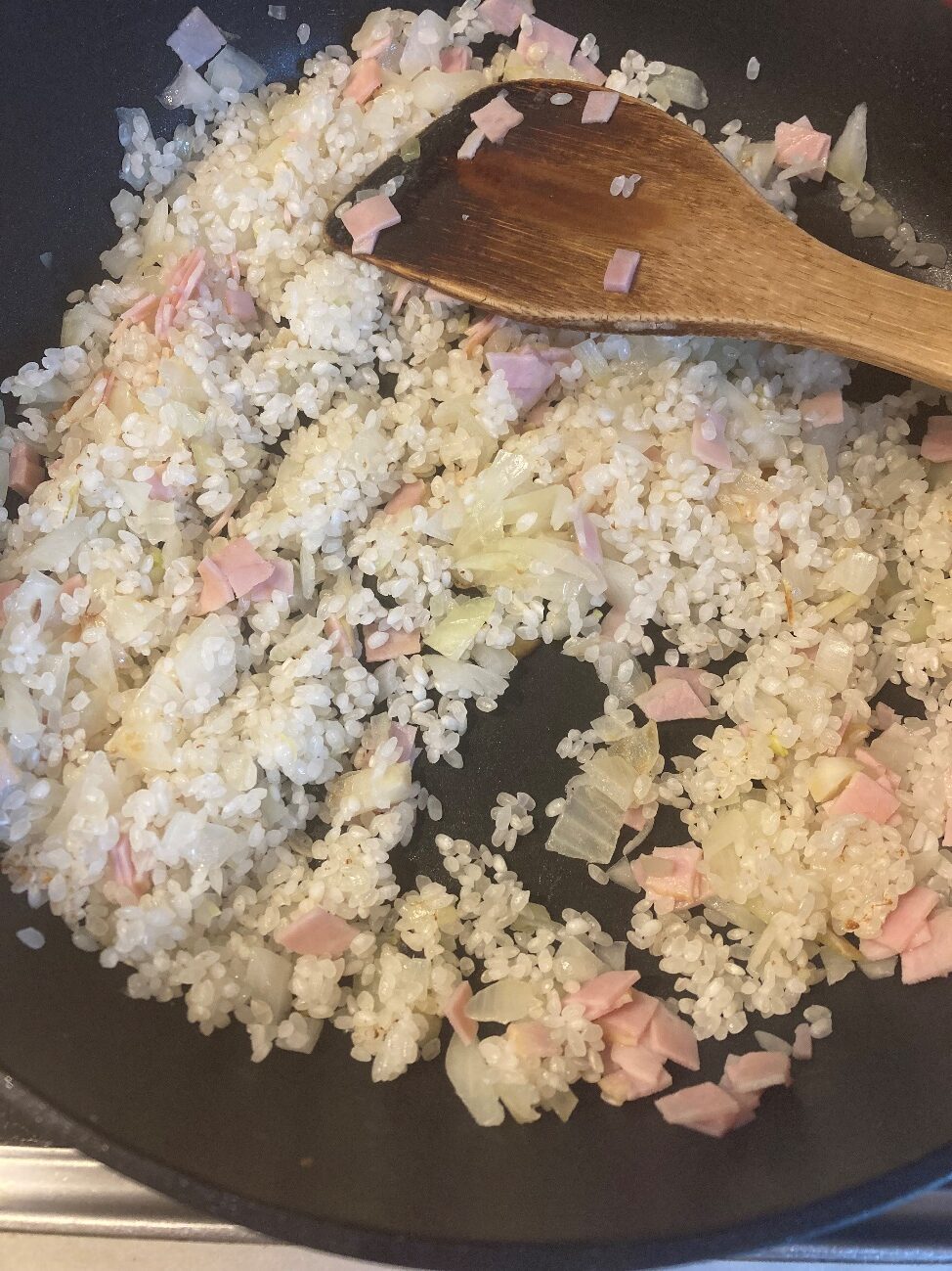 バターで玉ねぎを炒めてからお米をベーコンを加えて炒め合わせる