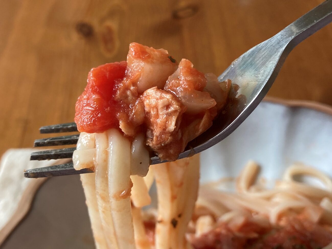 フォークですくい上げた完成した業務スーパーのオーガニックカットトマト缶詰で作ったトマトうどんのアップ