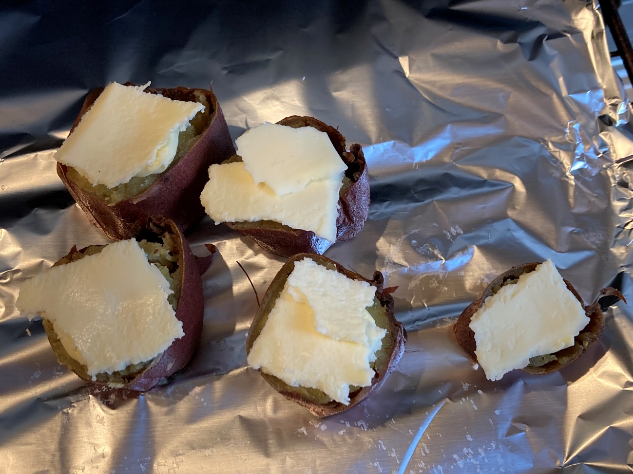 アルミホイルに断面を上にした焼き芋を置いて、バターとチーズをのせる
