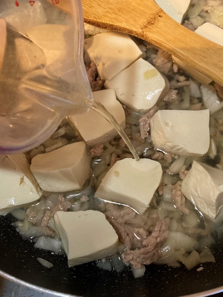 炒めた豚ひき肉と玉ねぎに豆腐と業務スーパーの塩鍋の素を加える