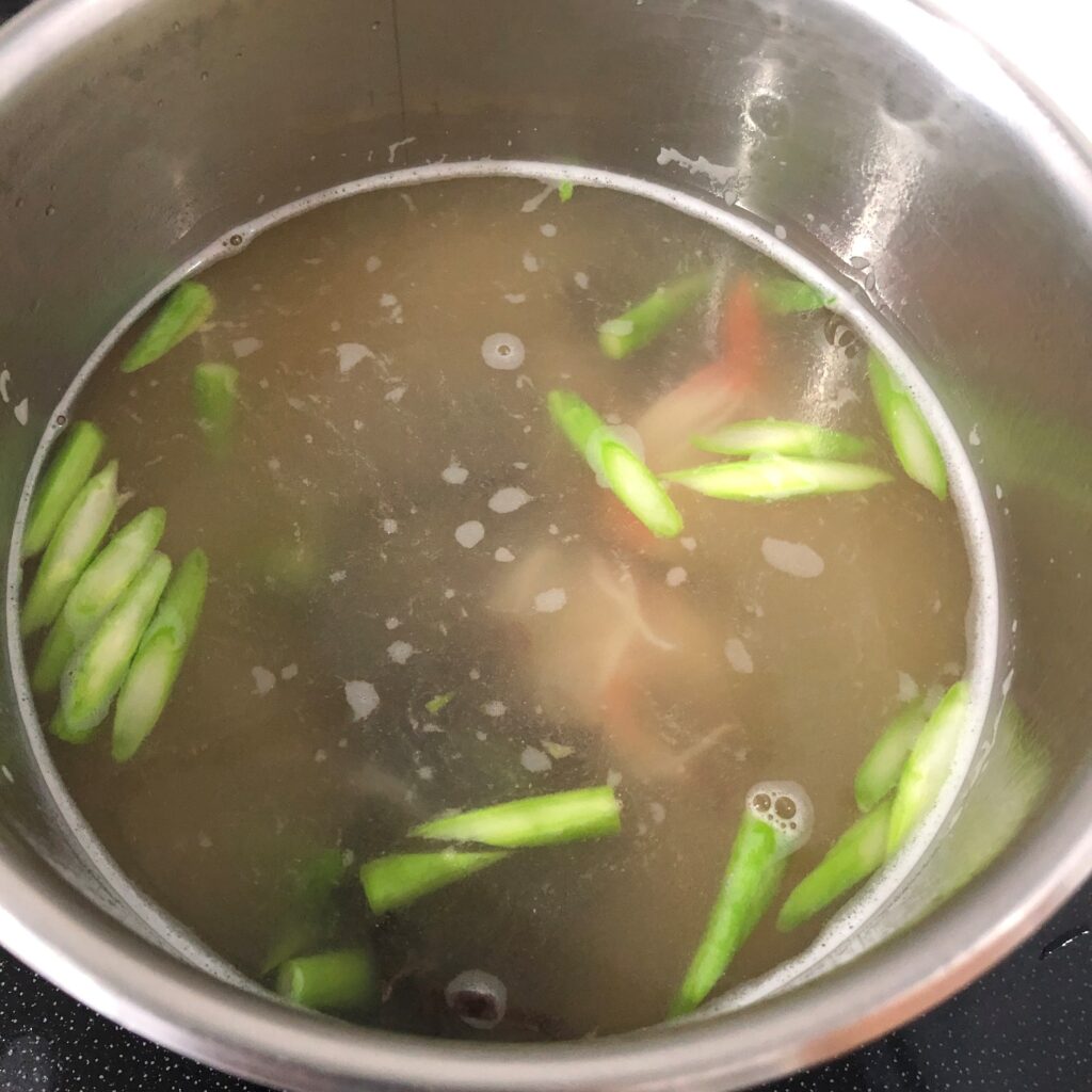 鍋にお湯を沸かし、調味料・スライスきくらげ・カニカマ・アスパラを加える