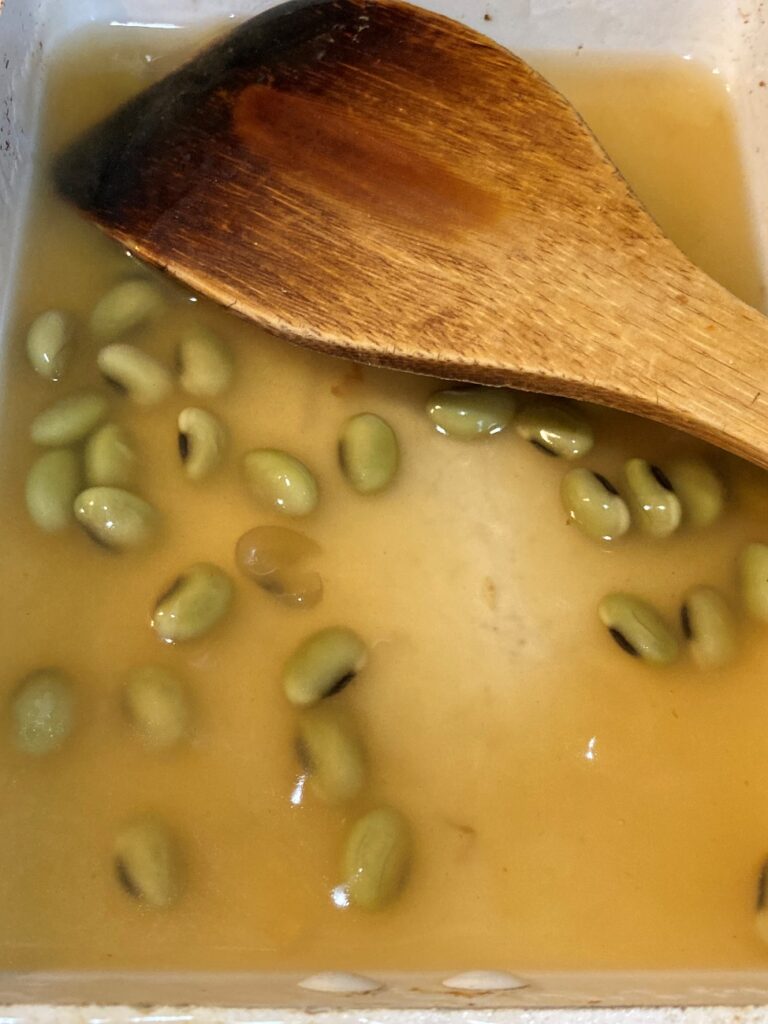 別のフライパンに入れた業務スーパーの寄せ鍋つゆとむき枝豆に水溶き片栗粉を加える